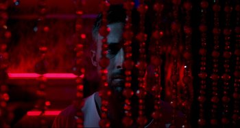 Movie still from “Only God Forgives” (2013), directed by Nicolas Winding Refn – A man standing in front of red beads in a dark room; Close Up shot, Low angle