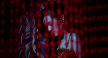 Movie still from “Only God Forgives” (2013), directed by Nicolas Winding Refn – A woman in a red dress is sitting in front of a red curtain; Close Up shot, Low angle