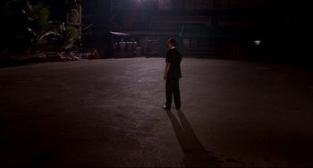 Movie still from “Only God Forgives” (2013), directed by Nicolas Winding Refn – A man standing in the dark in front of a building; Extreme Wide shot, High angle
