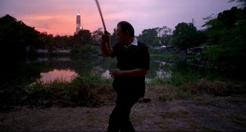 Movie still from “Only God Forgives” (2013), directed by Nicolas Winding Refn – A man holding a sword in his hand; Medium shot, Low angle