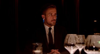 Movie still from “Only God Forgives” (2013), directed by Nicolas Winding Refn – A man sitting at a table with a glass of wine; Medium shot, Over the shoulder angle
