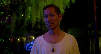 Movie still from “Only God Forgives” (2013), directed by Nicolas Winding Refn – A man wearing a white t - shirt and a necklace; Close Up shot, Low angle