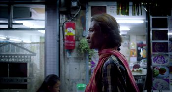 Movie still from “Only God Forgives” (2013), directed by Nicolas Winding Refn – A man with long hair standing in front of a building; Medium shot, Over the shoulder angle