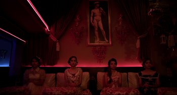 Movie still from “Only God Forgives” (2013), directed by Nicolas Winding Refn – Two women sitting on a couch in a dark room; Wide shot, Low angle