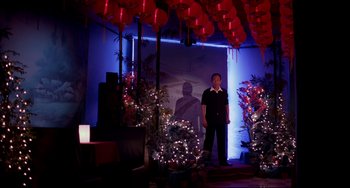 Movie still from “Only God Forgives” (2013), directed by Nicolas Winding Refn – A man standing in front of some christmas lights; Wide shot, Low angle