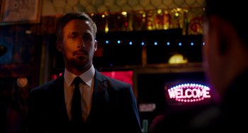 Movie still from “Only God Forgives” (2013), directed by Nicolas Winding Refn – A man wearing a suit and tie standing in front of a neon sign; Close Up shot, Over the shoulder angle