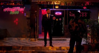 Movie still from “Only God Forgives” (2013), directed by Nicolas Winding Refn – A man in a suit standing on steps in front of a building; Wide shot, Over the shoulder angle