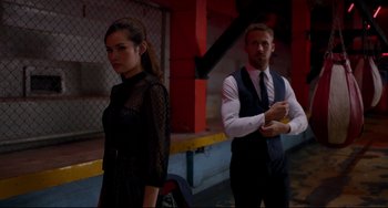 Movie still from “Only God Forgives” (2013), directed by Nicolas Winding Refn – A man and a woman standing next to each other in front of a building; Medium shot, Low angle