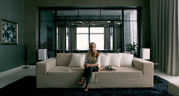 Movie still from “Only God Forgives” (2013), directed by Nicolas Winding Refn – A woman sitting on top of a white couch in a room; Wide shot, Overhead angle