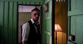 Movie still from “Only God Forgives” (2013), directed by Nicolas Winding Refn – A man in a suit and tie standing in front of a green door; Medium shot, Low angle