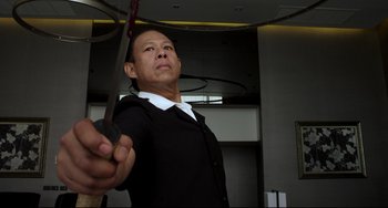 Movie still from “Only God Forgives” (2013), directed by Nicolas Winding Refn – A man holding a pair of scissors in a room; Medium shot, Low angle