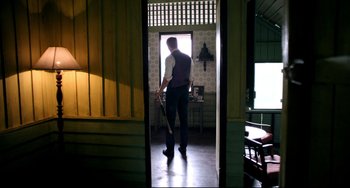 Movie still from “Only God Forgives” (2013), directed by Nicolas Winding Refn – A man holding a baseball bat while standing in a room; Wide shot, Low angle