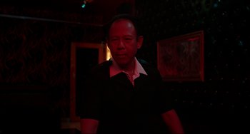 Movie still from “Only God Forgives” (2013), directed by Nicolas Winding Refn – A man standing in a dark room in front of a painting; Medium shot, Low angle