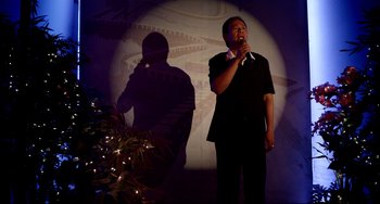 Movie still from “Only God Forgives” (2013), directed by Nicolas Winding Refn – A man standing on a stage with a microphone in his hand; Medium shot, Low angle