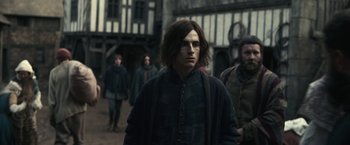 Movie still from “The King” (2019), directed by David Michôd – A group of people walking down a street; Medium shot, Over the shoulder angle