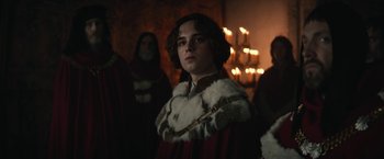 Movie still from “The King” (2019), directed by David Michôd – A man in a red robe and a white mantle; Medium shot, Over the shoulder angle