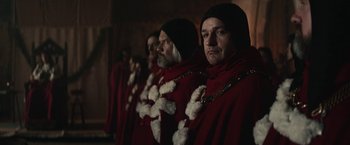 Movie still from “The King” (2019), directed by David Michôd – A group of men in red robes standing next to each other; Medium shot, Over the shoulder angle