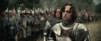 Movie still from “The King” (2019), directed by David Michôd – A group of men in medieval garb are standing in a line; Medium shot, Over the shoulder angle