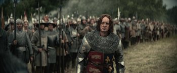 Movie still from “The King” (2019), directed by David Michôd – A group of men in chainmail and armor are marching; Medium shot, Over the shoulder angle