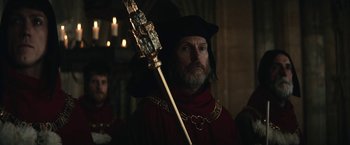 Movie still from “The King” (2019), directed by David Michôd – A man with a beard holding a golden scepter in his hand; Medium shot, Over the shoulder angle