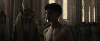 Movie still from “The King” (2019), directed by David Michôd – A young man is standing in front of a mirror; Medium shot, Low angle