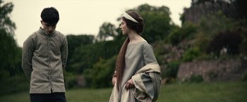 Movie still from “The King” (2019), directed by David Michôd – A woman in a long dress and a long braid; Medium shot, Over the shoulder angle