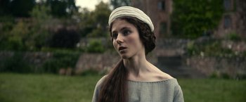 Movie still from “The King” (2019), directed by David Michôd – A woman with long brown hair wearing a white hat; Close Up shot, Over the shoulder angle