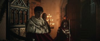 Movie still from “The King” (2019), directed by David Michôd – A group of people in a room with candles; Medium shot, Low angle