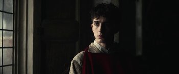 Movie still from “The King” (2019), directed by David Michôd – A young man wearing a red and white shirt; Close Up shot, Over the shoulder angle