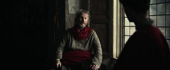 Movie still from “The King” (2019), directed by David Michôd – A man sitting in a chair in front of an open window; Medium shot, Over the shoulder angle