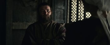 Movie still from “The King” (2019), directed by David Michôd – A man with a long beard is standing in a room; Medium shot, Over the shoulder angle