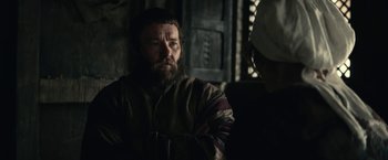 Movie still from “The King” (2019), directed by David Michôd – A man with a long beard is looking at the camera; Medium shot, Over the shoulder angle