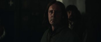 Movie still from “The King” (2019), directed by David Michôd – A man with long black hair is looking at the camera; Close Up shot, Over the shoulder angle