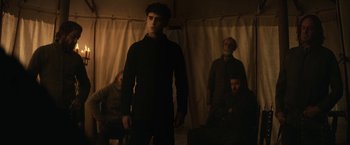 Movie still from “The King” (2019), directed by David Michôd – A group of people standing in a dark room; Medium shot, Low angle