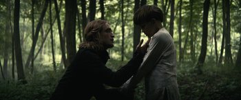 Movie still from “The King” (2019), directed by David Michôd – A man and a boy in the woods touching each other; Medium shot, Over the shoulder angle