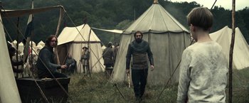 Movie still from “The King” (2019), directed by David Michôd – A man with a long beard in front of some tents; Wide shot, Low angle