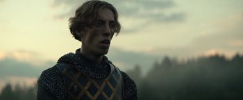 Movie still from “The King” (2019), directed by David Michôd – A man in chain mail standing in front of a forest; Close Up shot, Low angle