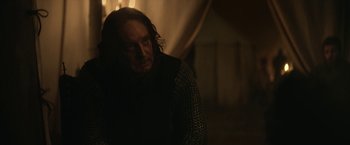 Movie still from “The King” (2019), directed by David Michôd – A man in chain mail standing next to a wall; Close Up shot, Over the shoulder angle