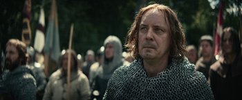 Movie still from “The King” (2019), directed by David Michôd – A man in chain mail is standing in front of a group of people; Close Up shot, Low angle