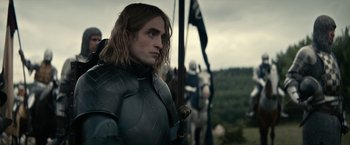 Movie still from “The King” (2019), directed by David Michôd – A person wearing armor and holding a sword; Medium shot, Low angle
