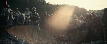 Movie still from “The King” (2019), directed by David Michôd – A group of people in medieval costumes standing in a field; Wide shot, Low angle