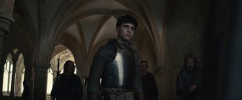 Movie still from “The King” (2019), directed by David Michôd – A young man in a suit of armor standing in a hallway; Medium shot, Low angle