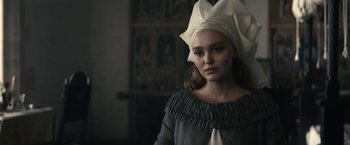 Movie still from “The King” (2019), directed by David Michôd – A young woman wearing a head scarf and a dress; Close Up shot, Low angle