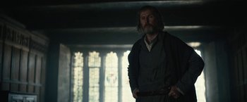 Movie still from “The King” (2019), directed by David Michôd – A man standing in front of stained glass windows; Medium shot, Low angle