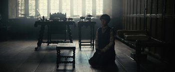 Movie still from “The King” (2019), directed by David Michôd – A woman sitting on the floor in a room; Medium shot, High angle