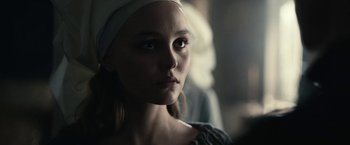 Movie still from “The King” (2019), directed by David Michôd – A young woman wearing a head scarf looking at the camera; Close Up shot, Over the shoulder angle