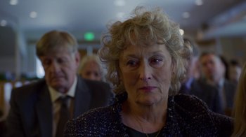 Movie still from “The Laundromat” (2019), directed by Steven Soderbergh – An older woman is looking at the camera; Close Up shot, Over the shoulder angle