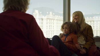 Movie still from “The Laundromat” (2019), directed by Steven Soderbergh – Two women and a child sitting in front of a window; Medium shot, Over the shoulder angle