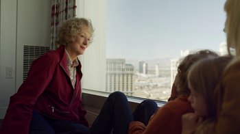 Movie still from “The Laundromat” (2019), directed by Steven Soderbergh – Two people sitting in front of a window with a view of a city; Close Up shot, Over the shoulder angle