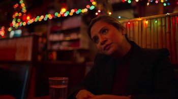 Movie still from “The Laundromat” (2019), directed by Steven Soderbergh – A woman sitting at a table with a glass in front of her; Close Up shot, Low angle